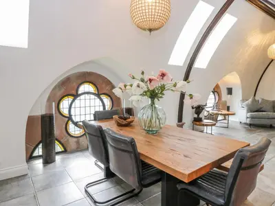 a dining room with a table with chairs and a vase with flowers at Penthouse St Mary's Church in Moffat
