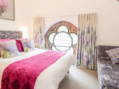a bedroom with a large bed and a window at Penthouse St Mary's Church in Moffat