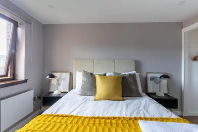 a bedroom with a large bed with a yellow pillow at Stunning 1 Bed Merchant City Apartment with Parking in Glasgow