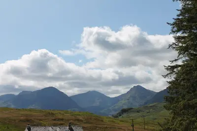 a person standing on a bench looking at the mountains at Loch Arklet House in Stirling