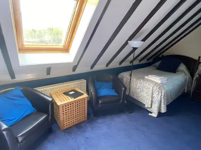 a bedroom with a bed and a chair and a table at Loch Arklet House in Stirling