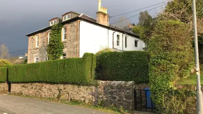an ivy covered wall in front of a house at Fasgadh Rooms in Tarbert