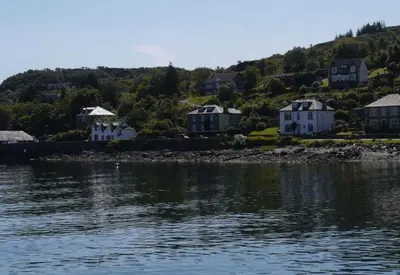 a group of houses on a hill next to the water at Fasgadh Rooms in Tarbert