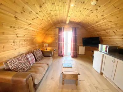 a living room with a couch in a log cabin at Pond View Pod 1 with Outdoor Hot Tub - Fife - Loch Leven - Lomond Hills in Kelty