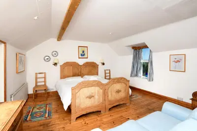 a bedroom with a wooden bed and a couch at Craigadam Country House Hotel in Kirkpatrick Durham