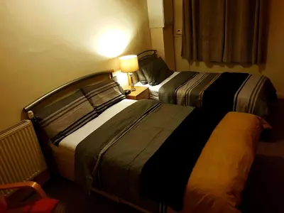 a hotel room with two beds and a lamp at Glen View Apartments in Port Glasgow