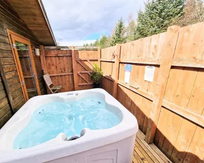 a hot tub on a deck with a wooden fence at Lomond 6 with Private Hot Tub - Fife - Loch Leven - Lomond Hills in Kelty