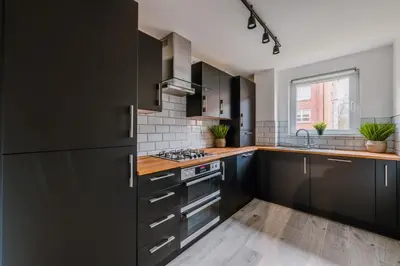 a kitchen with black cabinets and a sink at RelaxingSleep Apartments in Glasgow