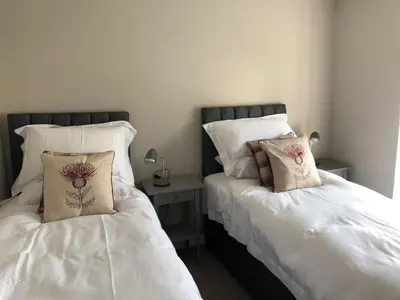 a bedroom with two beds with white sheets and a side table at Garron House in Auchterarder