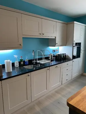 a kitchen with white cabinets and black counter tops at Garron House in Auchterarder