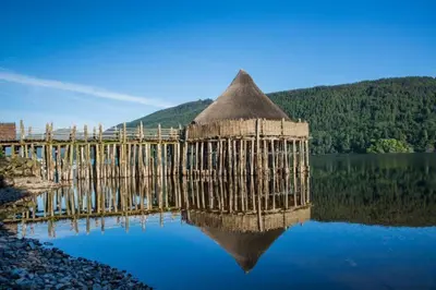 a bridge over a lake with its reflection in the water at Cosy Rowan woodland lodge no1 in Killin