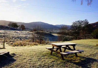 a picnic table sitting on top of a field at Cosy & compact Rowan Lodge no2 in Killin