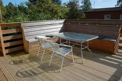 a table and two chairs sitting on a deck at Woodland Gean Lodge in Killin