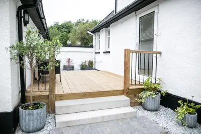 a porch with a wooden deck with potted plants at Glenview Luss in Luss