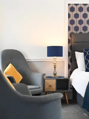 a bedroom with a bed and a chair and a lamp at MacKays in Oban