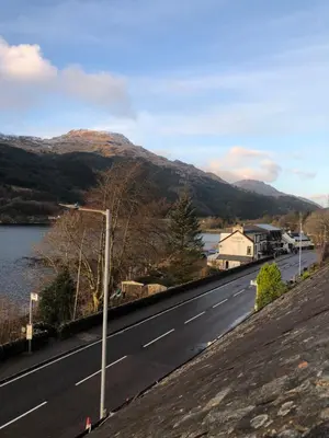 a road with a view of a lake and mountains at Amazing Alps and Loch views - HOT TUB and pet friendly in Arrochar