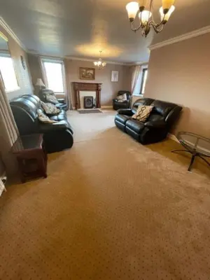a living room with two leather couches and a fireplace at Carminnows Holiday Cottage in Carsphairn