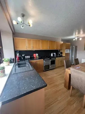 a kitchen with wooden cabinets and a counter top at Carminnows Holiday Cottage in Carsphairn
