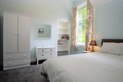 a bedroom with a bed and a dresser and a window at Upper Alta Apartment in Tighnabruaich