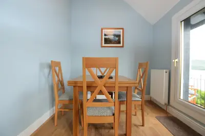 a table and chairs in a room with a window at Upper Alta Apartment in Tighnabruaich