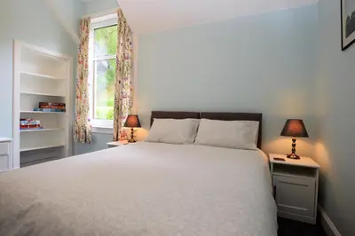 a bedroom with a large white bed with two lamps at Upper Alta Apartment in Tighnabruaich