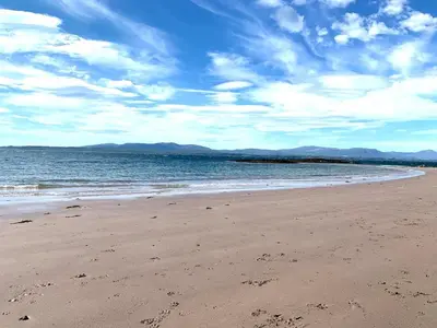 a beach with a cloudy sky and the ocean at Imperial Apartment in Oban