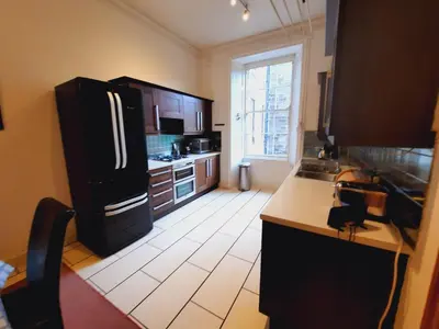 a kitchen with a black refrigerator and a white tile floor at Cornwall Street - 297 in Edinburgh