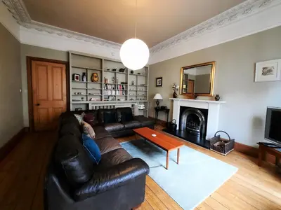 a living room with a leather couch and a fireplace at Cornwall Street - 297 in Edinburgh
