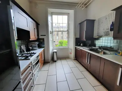 a kitchen with wooden cabinets and a large window at Cornwall Street - 297 in Edinburgh