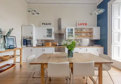 a kitchen with a wooden table and white chairs at Saxe Coburg Place - 325 in Edinburgh