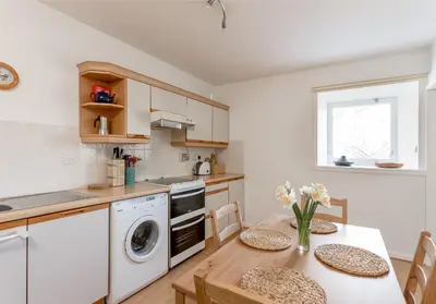 a kitchen with a table with chairs and a washing machine at Dean Path - 400 in Edinburgh