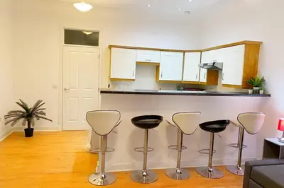 a kitchen with a counter and four stools at Cozy Nights - Ibrox Street in Glasgow