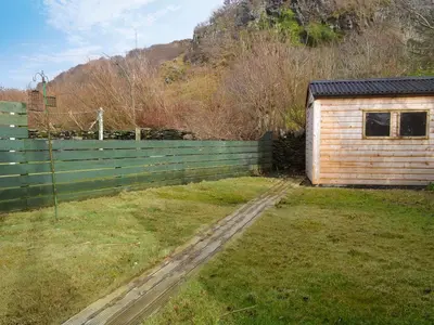 a wooden fence next to a house with a yard at Seaview Cottage in Ellanbeich