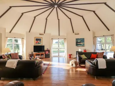 a living room with leather furniture and a large ceiling at The Roundhouse in Auchterarder