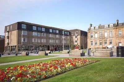 a park with flowers in front of a building at The Flat In The Square in Helensburgh