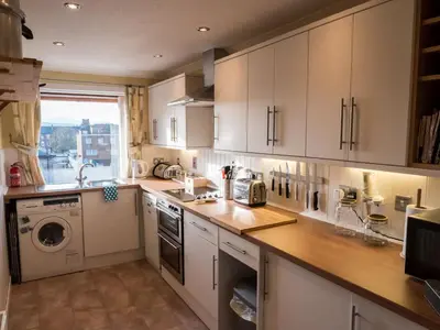 a kitchen with white cabinets and a washer and dryer at The Flat In The Square in Helensburgh