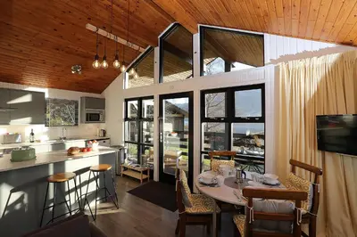 a kitchen and dining room with a table and some windows at Cosy Modern Nordic Lodge w/ Loch View & Log Burner in Lochearnhead