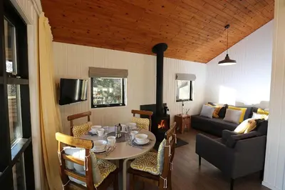 a living room with a table and a couch at Cosy Modern Nordic Lodge w/ Loch View & Log Burner in Lochearnhead
