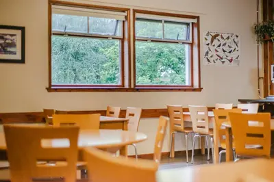 a dining room with tables and chairs and windows at Crianlarich Youth Hostel in Crianlarich