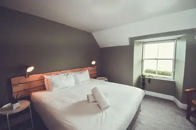 a bedroom with a large white bed with a window at Boreland Loch Tay in Aberfeldy
