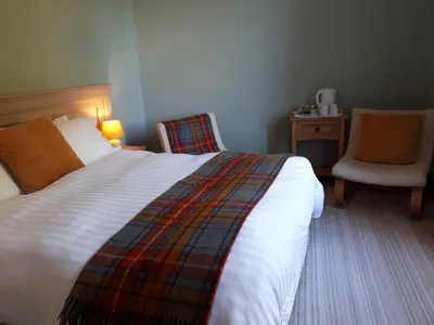 a hotel room with a bed and a chair at Corsewall Arms Guest House in Stranraer
