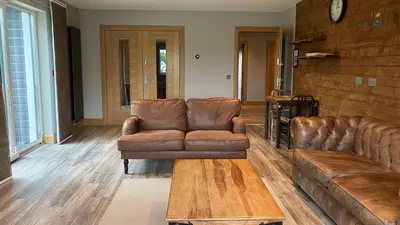 a living room with two leather couches and a coffee table at The Shack & Pods at Inchree in Corran