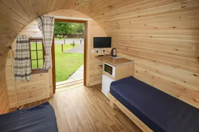 a small room with a bed in a wooden cabin at Posh Pod in Tyndrum