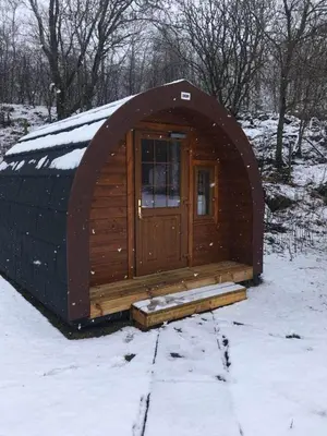 a wooden cabin with a door in the snow at Posh Pod in Tyndrum