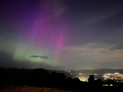 an aurora in the sky over a city at night at Stoneymollan over Loch Lomond in Balloch