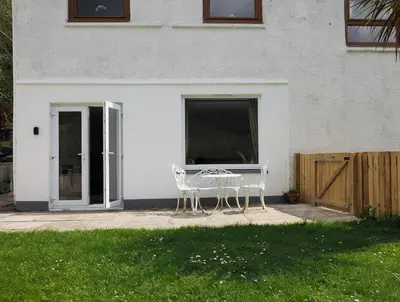 a white bench sitting in front of a house at Arrochar Alps Apartment in Arrochar