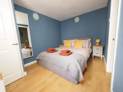 a bedroom with a bed with blue walls and a mirror at Arrochar Alps Apartment in Arrochar