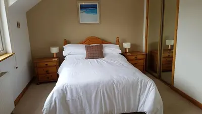 a bedroom with a large white bed and two dressers at The Curling Pond, Dalmally Road, Inveraray in Inveraray