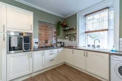 a kitchen with white cabinets and a window at The Stirling Townhouse in Stirling