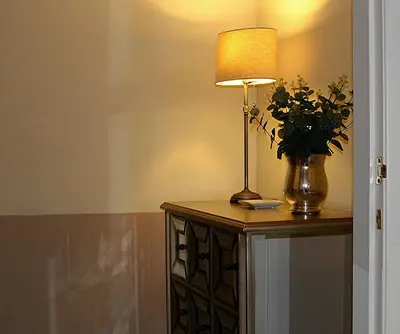 a lamp on a table with a vase of flowers at Linden Apartment in Stirling